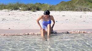 Daniela sitting on a pink sand beach