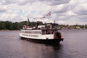 Båten Stockholms Ström 2 glider över vattnet med Stockholm i fjärran.