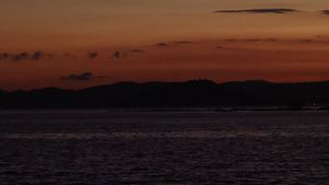 Multicoloured sunset viewed over the water from the side of a boat